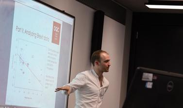 Lecturer standing in front of projector explaining plot